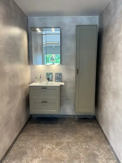 Showroom-badrum med salviagrön kommod och mikrocement-väggar