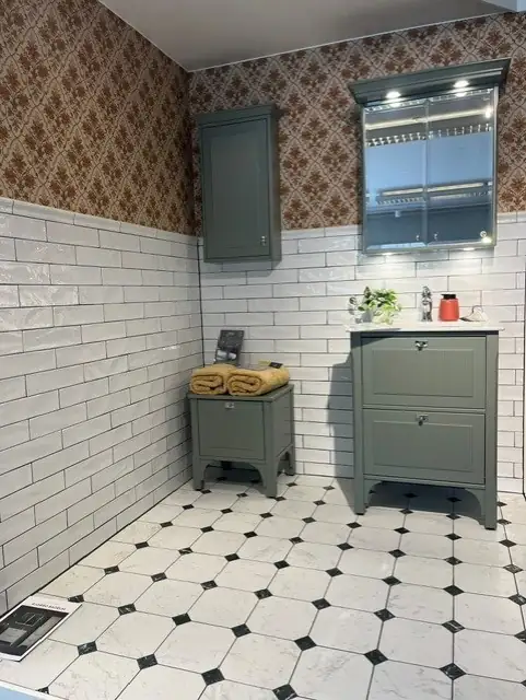 Lantligt showroom-badrum med grön kommod och vitt kakel