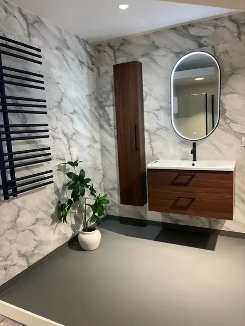 Showroom-badrum med marmorvägg, valnötskommod och handdukstork
