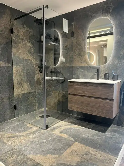 Showroom-badrum med mörk stenklinker, walk-in-dusch och valnötskommod