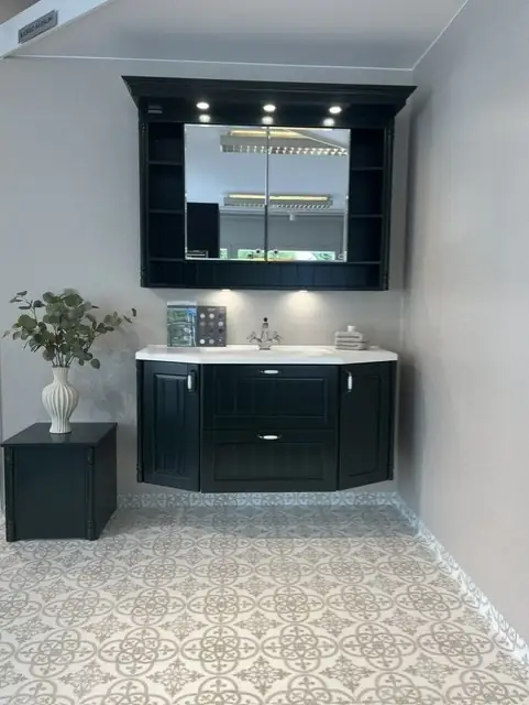 Lantligt showroom-badrum med svart kommod, spegelskåp och mönstrad klinker