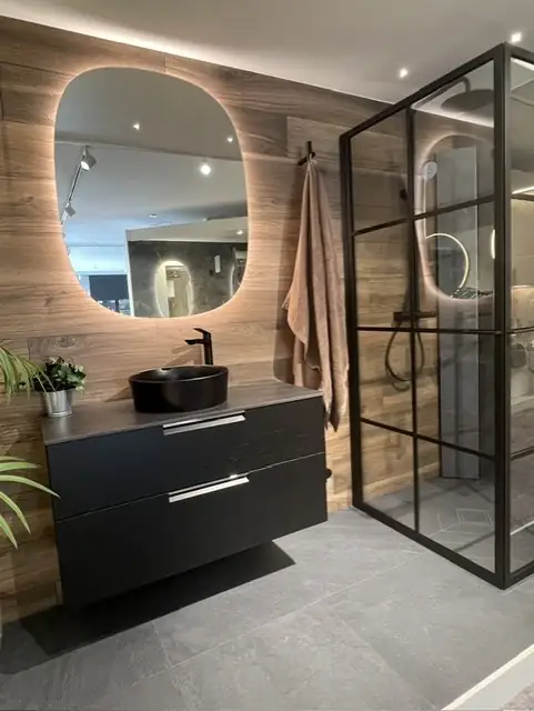 Showroom-badrum med träklädd vägg, svart kommod och svart duschvägg i glas